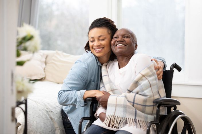A woman embracing an elderly woman in a wheelchair